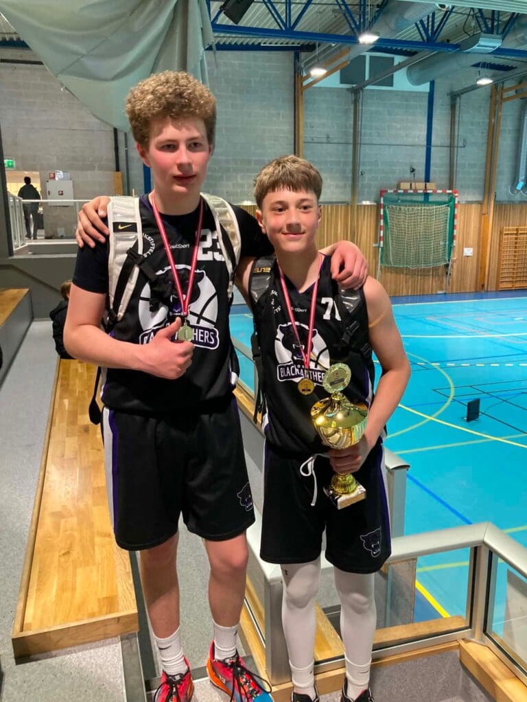 11 år gamle Fabian og Kristian fra Moss Black Panthers Basketball smiler med medaljer og en pokal etter et regionmesterskap i Ås.